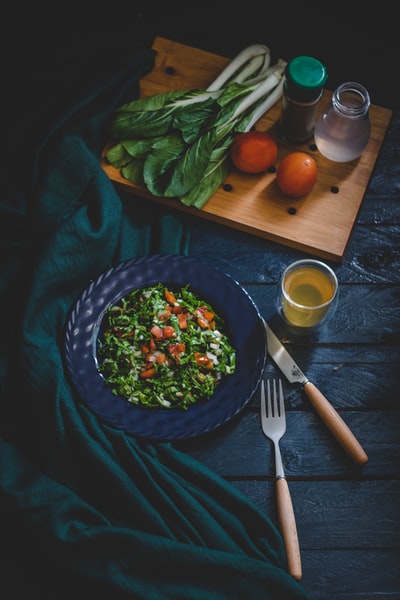 用叉子、刀和玻璃杯盛在碗里的蔬菜沙拉